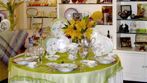 Dining room with a table set for a meal, shelves displaying decorative items, and a yellow wall.
